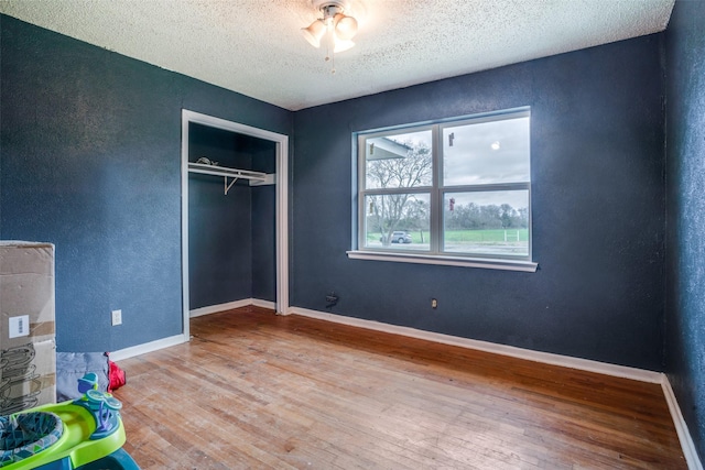 unfurnished bedroom featuring a textured ceiling, light hardwood / wood-style flooring, and a closet