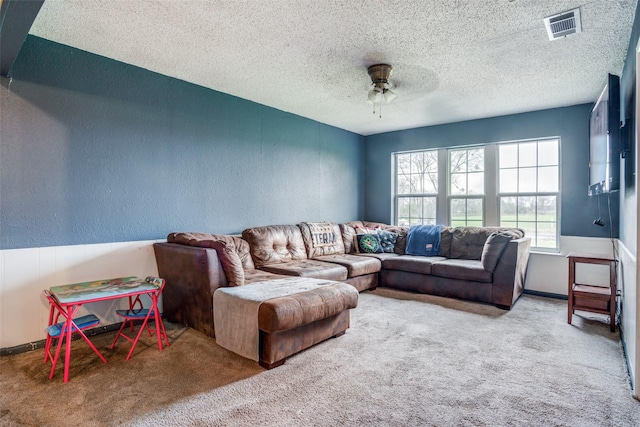 living room with carpet flooring, ceiling fan, and a textured ceiling