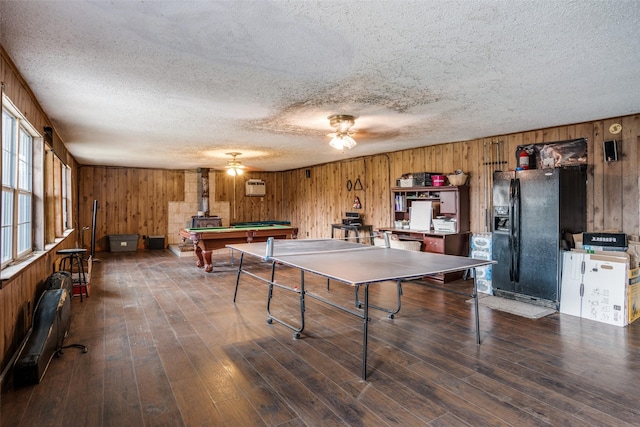 game room featuring dark wood-type flooring, a wall mounted air conditioner, billiards, wood walls, and a textured ceiling