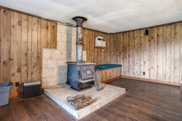 room details with a textured ceiling, hardwood / wood-style flooring, an AC wall unit, and wooden walls