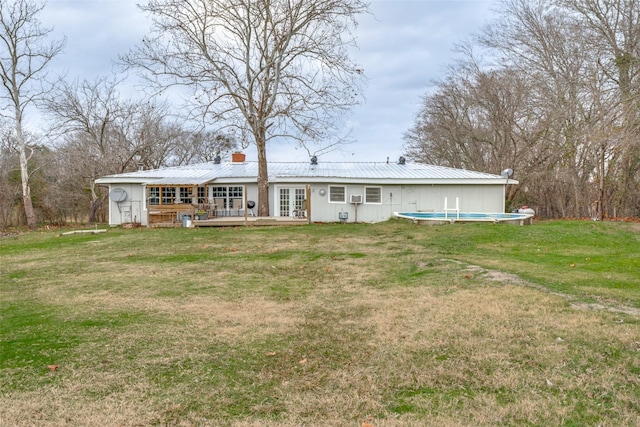 rear view of property featuring french doors, a yard, and a swimming pool side deck