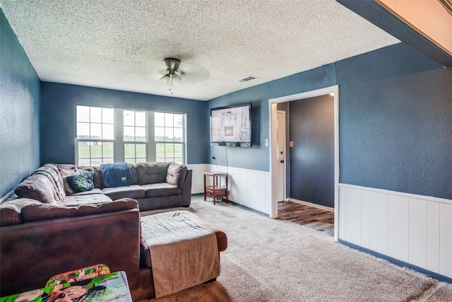 living room featuring carpet flooring, a textured ceiling, and ceiling fan