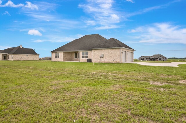 571 N Armstrong Rd, Venus, TX 76084 - back of property with concrete driveway, a lawn, central AC unit, and a garage