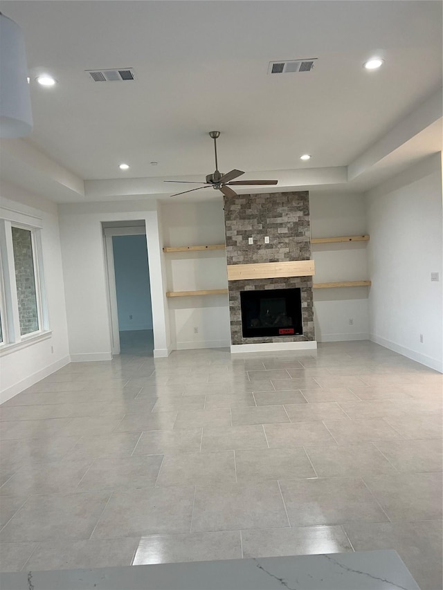 unfurnished living room with a stone fireplace, ceiling fan, and light tile patterned flooring