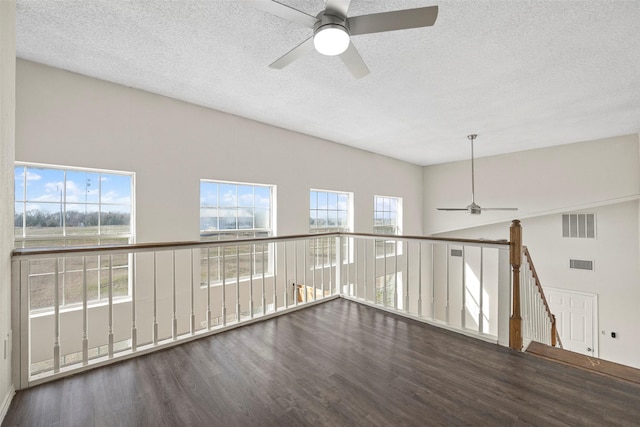 empty room with ceiling fan, plenty of natural light, wood-type flooring, and lofted ceiling