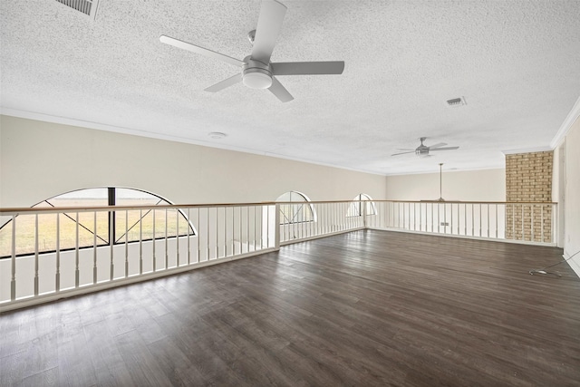 spare room featuring a textured ceiling, ceiling fan, crown molding, and dark wood-type flooring