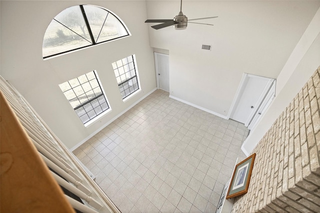 unfurnished living room featuring a towering ceiling and ceiling fan