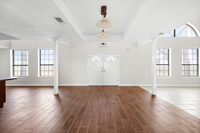 foyer entrance featuring a raised ceiling, plenty of natural light, and dark hardwood / wood-style flooring