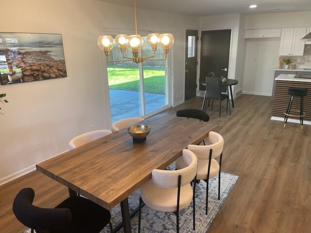 dining area with dark hardwood / wood-style flooring and an inviting chandelier