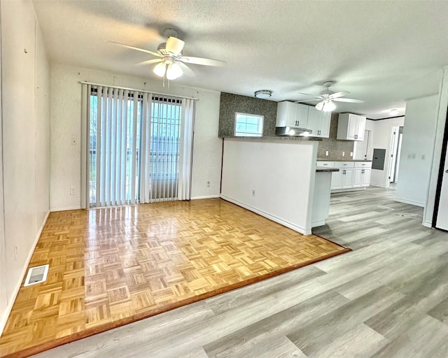 kitchen featuring white cabinetry, ceiling fan, light hardwood / wood-style flooring, backsplash, and a textured ceiling