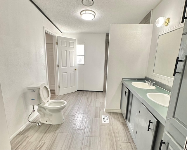 bathroom with vanity, a textured ceiling, and toilet