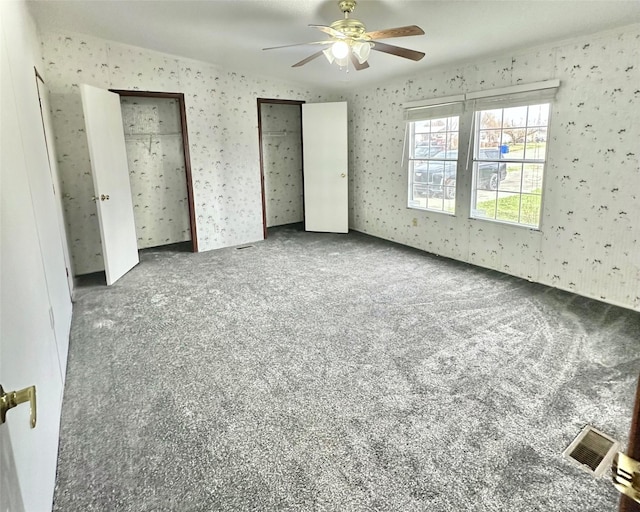 unfurnished bedroom with ceiling fan, carpet floors, and two closets