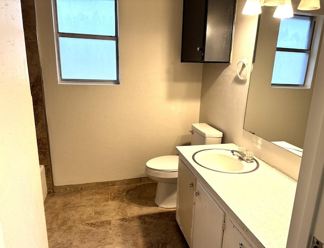 bathroom with a wealth of natural light, vanity, and toilet