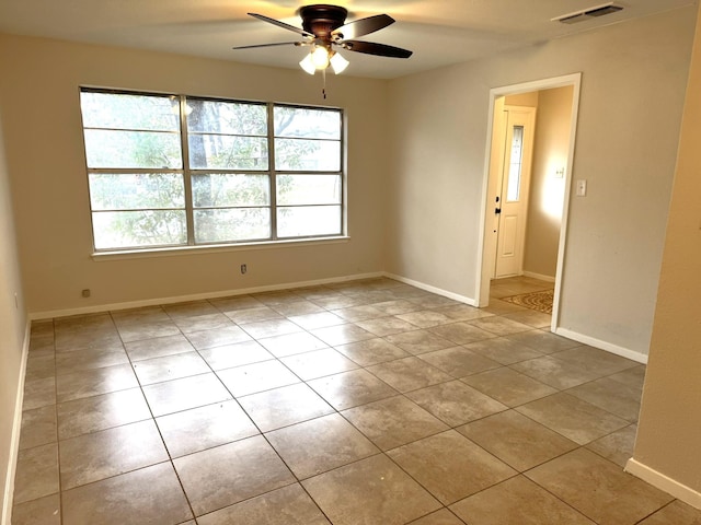 tiled spare room featuring a wealth of natural light and ceiling fan