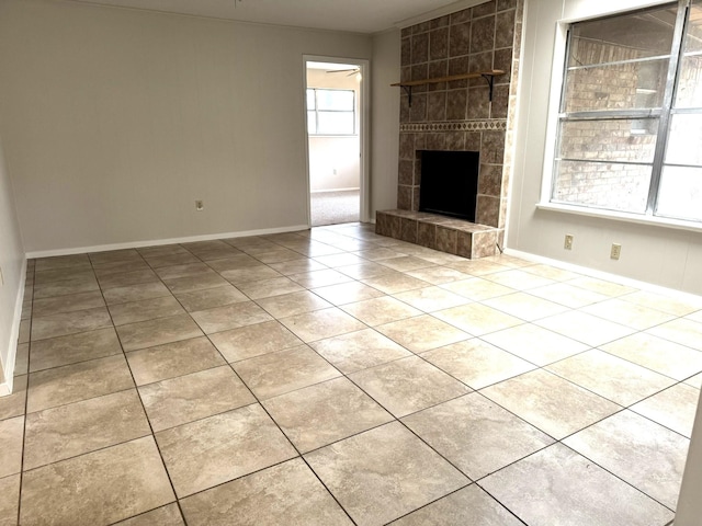 unfurnished living room with a tiled fireplace and light tile patterned flooring