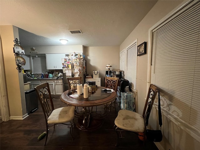 dining space with dark wood-type flooring and a textured ceiling