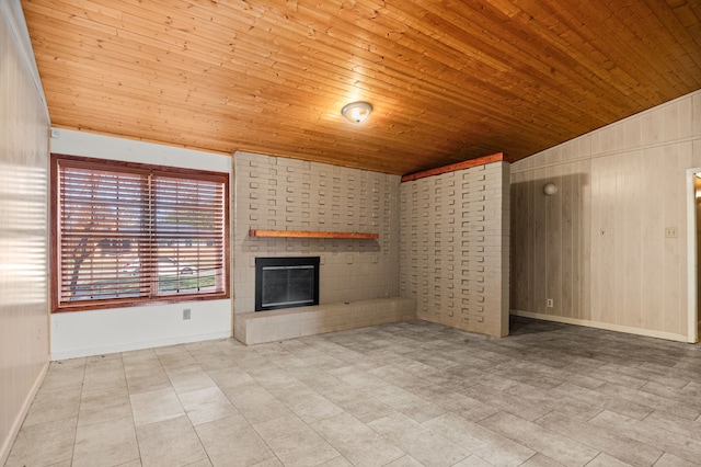 unfurnished living room featuring wood walls, wood ceiling, and a brick fireplace