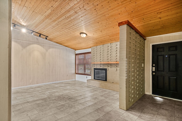 unfurnished living room with a fireplace, track lighting, wood walls, and wood ceiling