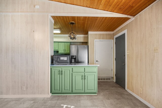 kitchen featuring stainless steel fridge, wooden walls, pendant lighting, and green cabinetry