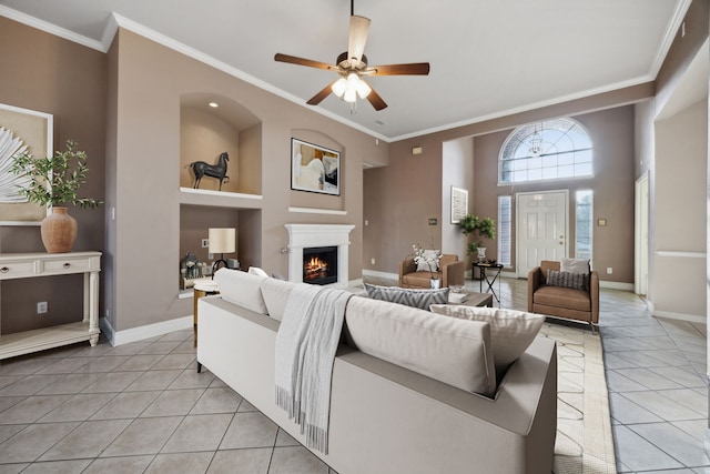 tiled living room with ceiling fan, ornamental molding, and built in shelves