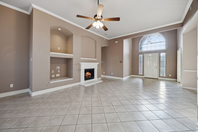 unfurnished living room featuring ceiling fan, built in features, light tile patterned floors, and crown molding