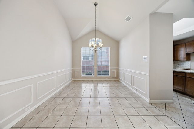 unfurnished dining area with light tile patterned floors, an inviting chandelier, and lofted ceiling