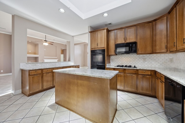 kitchen featuring light stone countertops, a center island, light tile patterned floors, and black appliances