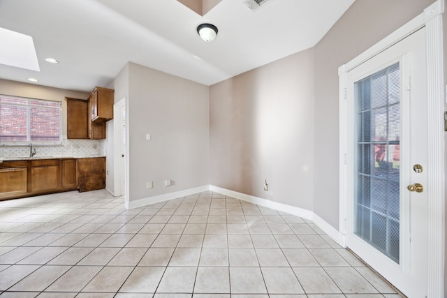 interior space featuring light tile patterned flooring, sink, and a skylight