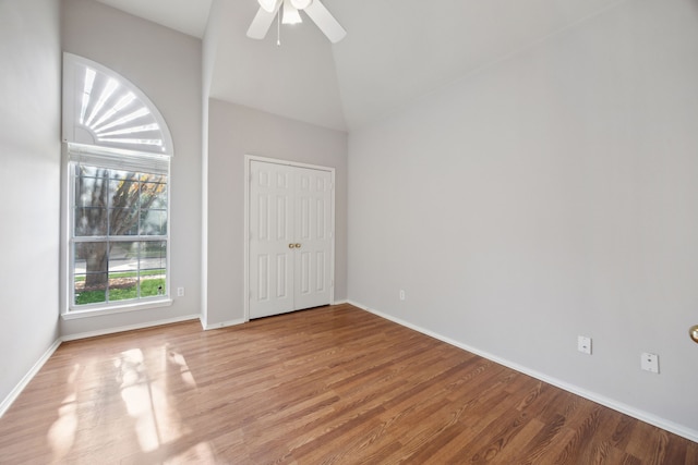 unfurnished bedroom with ceiling fan, high vaulted ceiling, and wood-type flooring