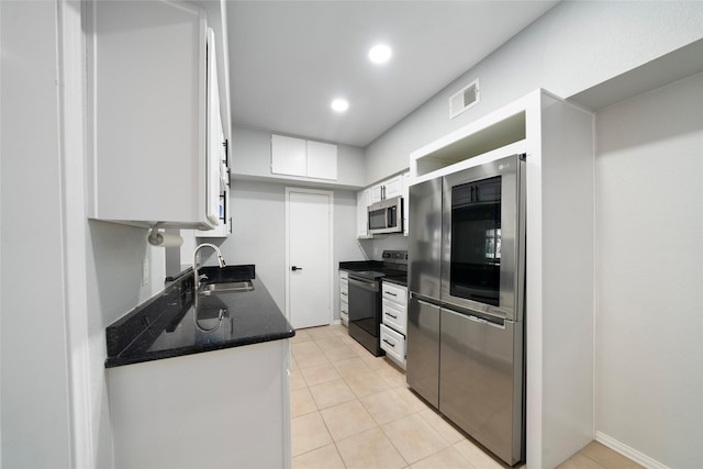 kitchen featuring dark stone counters, white cabinets, sink, light tile patterned flooring, and stainless steel appliances