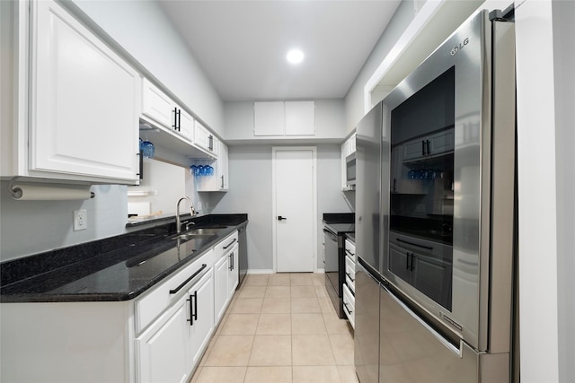 kitchen with dark stone counters, stainless steel appliances, sink, light tile patterned floors, and white cabinetry