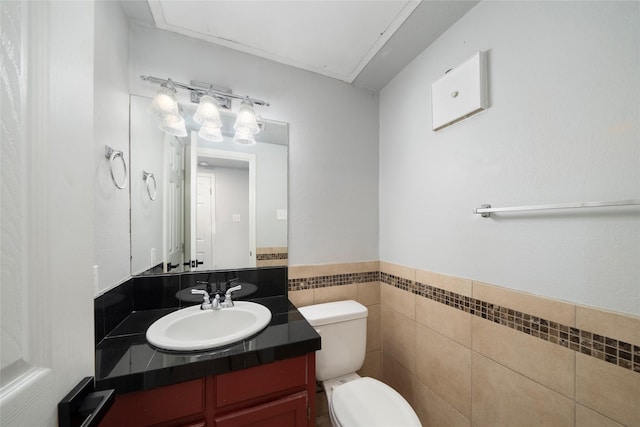 bathroom with vanity, toilet, and tile walls