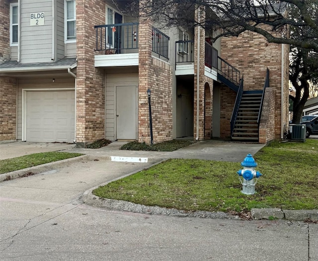 doorway to property with a balcony, a garage, and central air condition unit