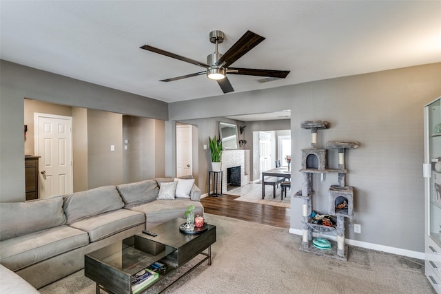 living room featuring ceiling fan, light colored carpet, and a brick fireplace