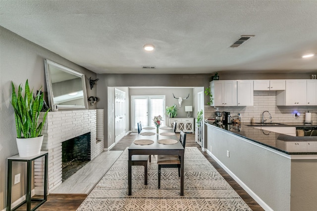 dining room featuring hardwood / wood-style floors, a textured ceiling, a brick fireplace, and sink