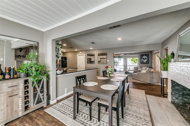 dining space featuring ceiling fan, light hardwood / wood-style floors, and a brick fireplace