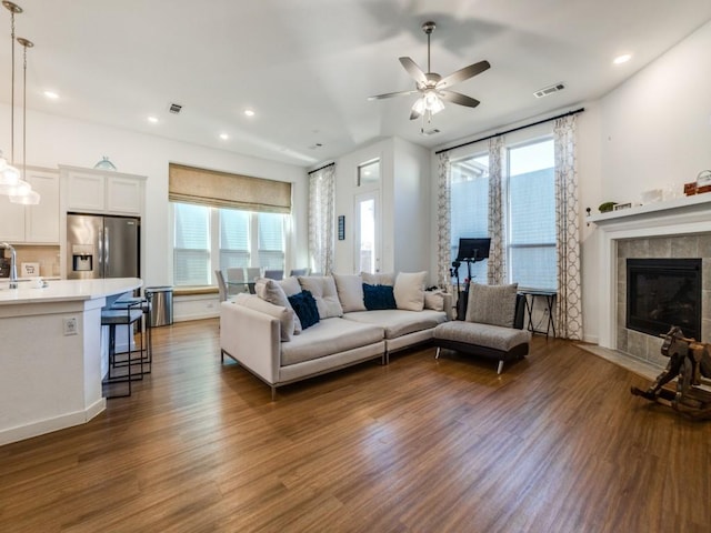 living room with ceiling fan, dark hardwood / wood-style floors, and a tile fireplace