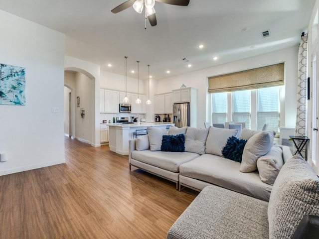 living room with light hardwood / wood-style flooring and ceiling fan