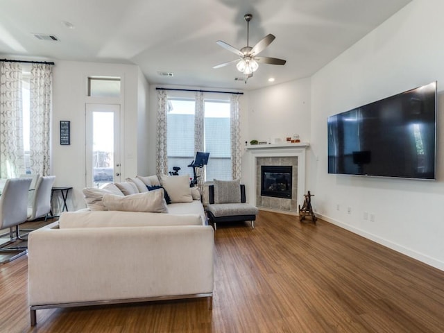 living room featuring hardwood / wood-style flooring, a tiled fireplace, and ceiling fan