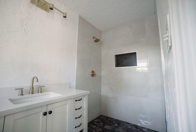 bathroom with a tile shower and vanity