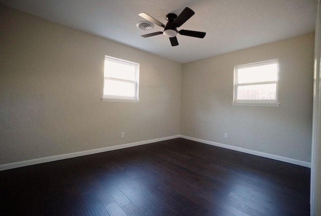 spare room featuring dark wood-type flooring, ceiling fan, and a healthy amount of sunlight