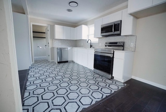 kitchen featuring backsplash, white cabinets, stainless steel appliances, and ornamental molding