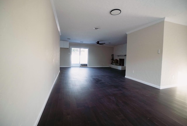 unfurnished living room featuring ceiling fan, dark hardwood / wood-style flooring, ornamental molding, and a brick fireplace