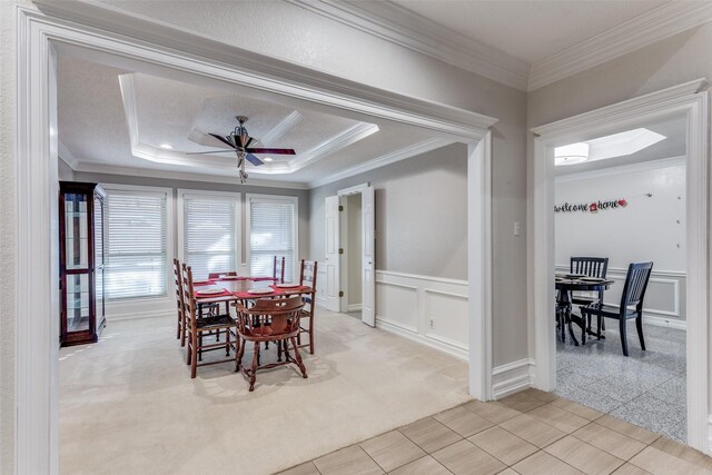 dining room with a raised ceiling, light colored carpet, and crown molding