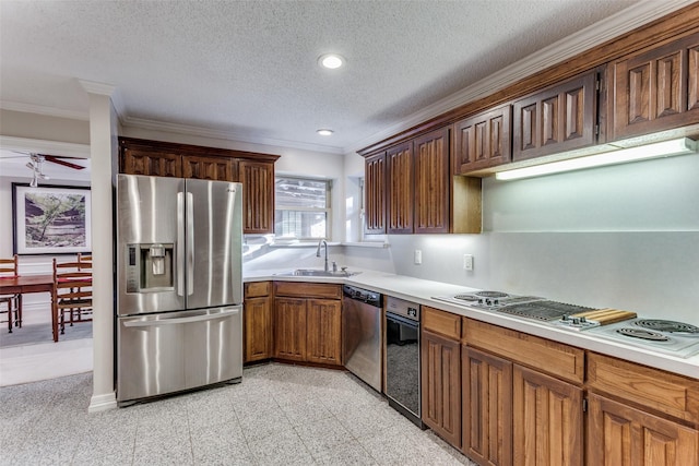 kitchen featuring appliances with stainless steel finishes, a textured ceiling, ceiling fan, crown molding, and sink