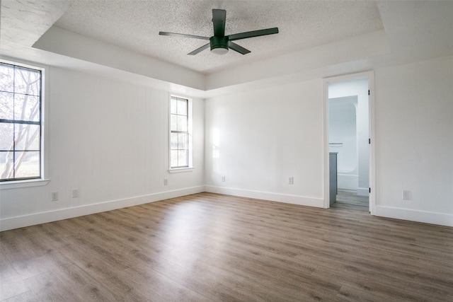 unfurnished room featuring wood-type flooring, a raised ceiling, and ceiling fan