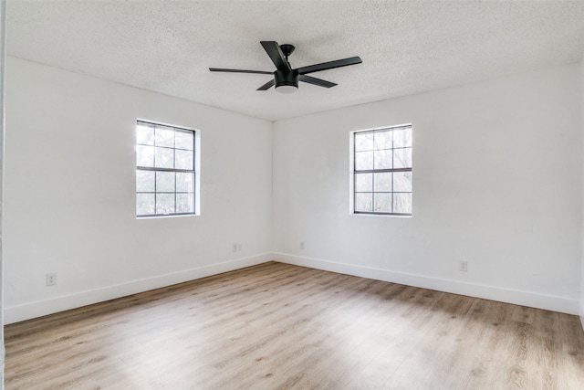 empty room with light wood-type flooring, a textured ceiling, and a wealth of natural light