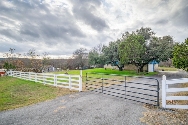 view of gate with a lawn and a rural view