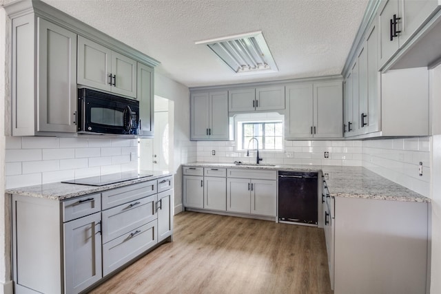 kitchen with decorative backsplash, sink, light hardwood / wood-style flooring, and black appliances