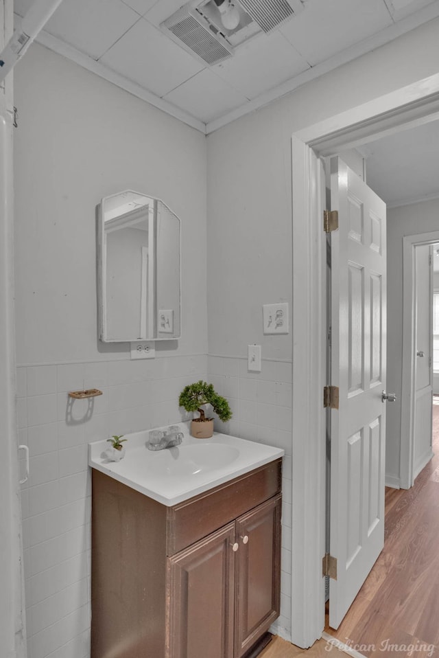 bathroom with hardwood / wood-style flooring, vanity, and tile walls